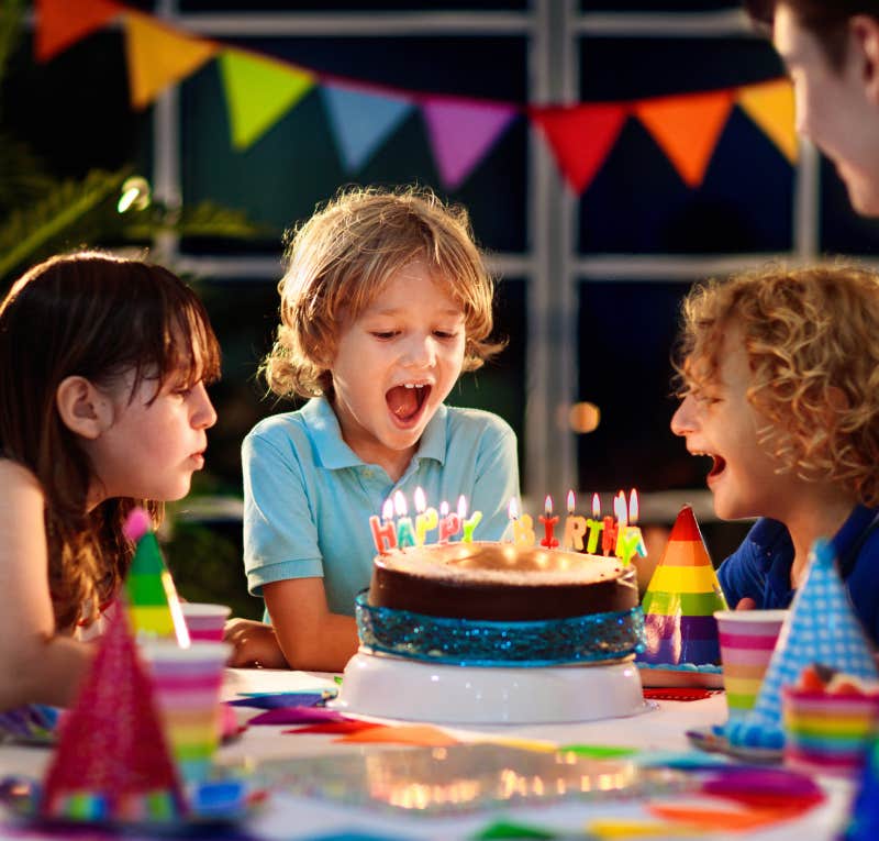 child blowing out birthday candles at party