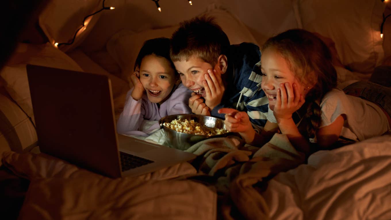 Shot of three young children using a laptop in a blanket fort