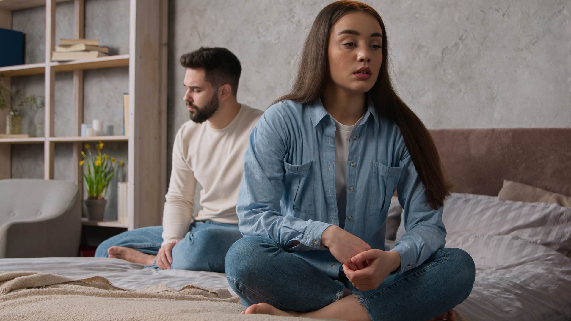 Woman looking upset sitting turned away from her boyfriend.