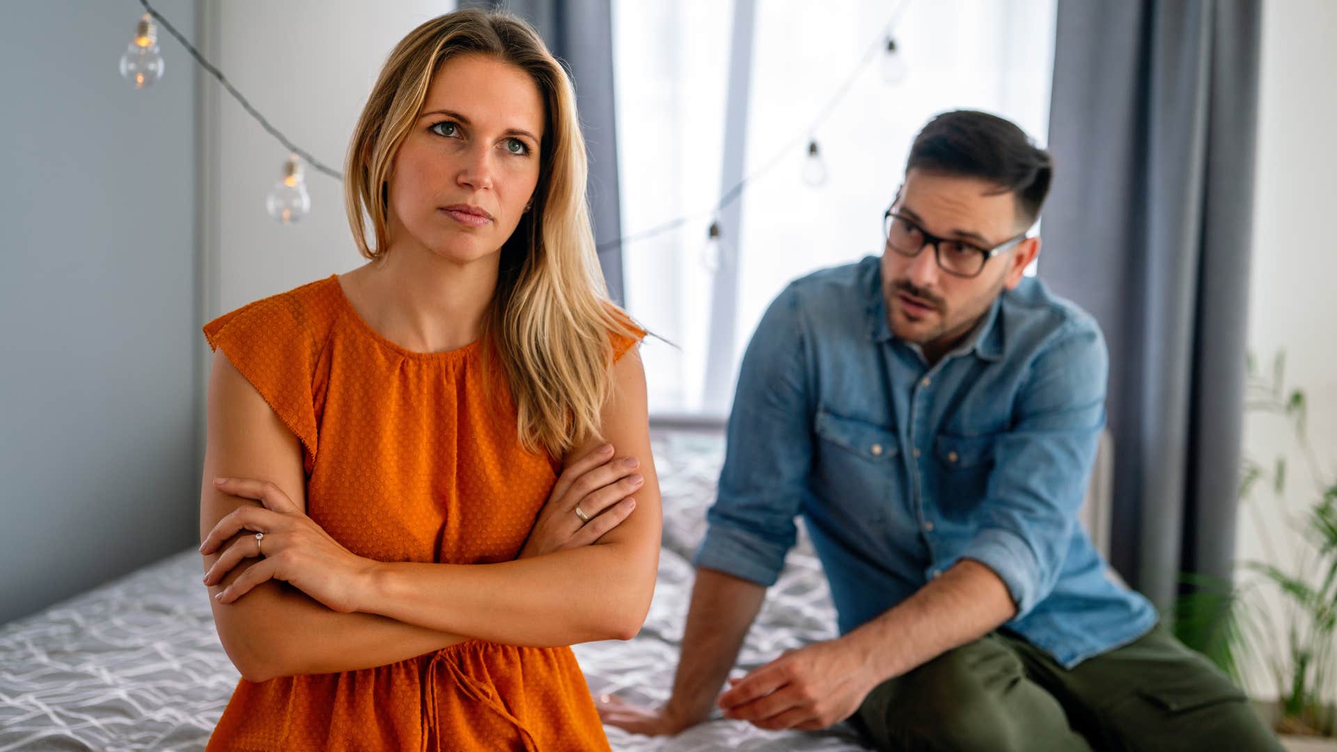 Woman crossing her arms while her boyfriend argues with her.