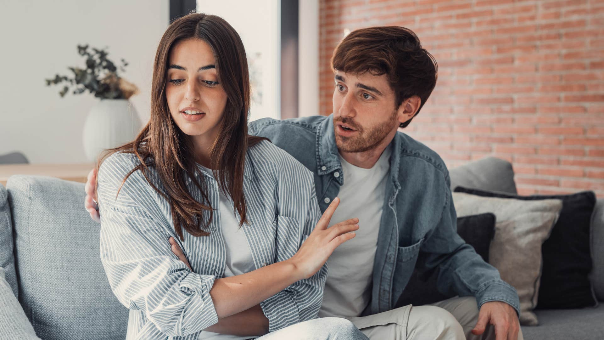 Couple arguing on a couch together.