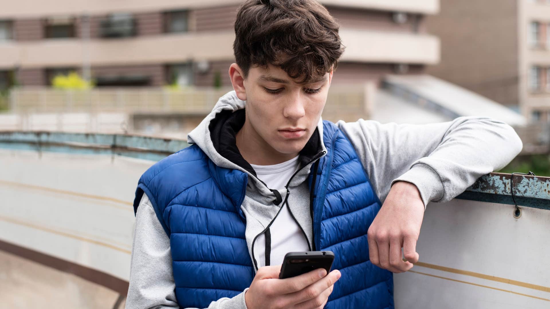 Young boy looking upset while texting.