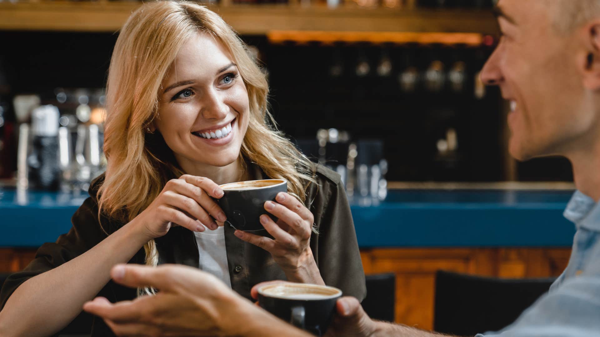 Woman smiling and drinking coffee with a man