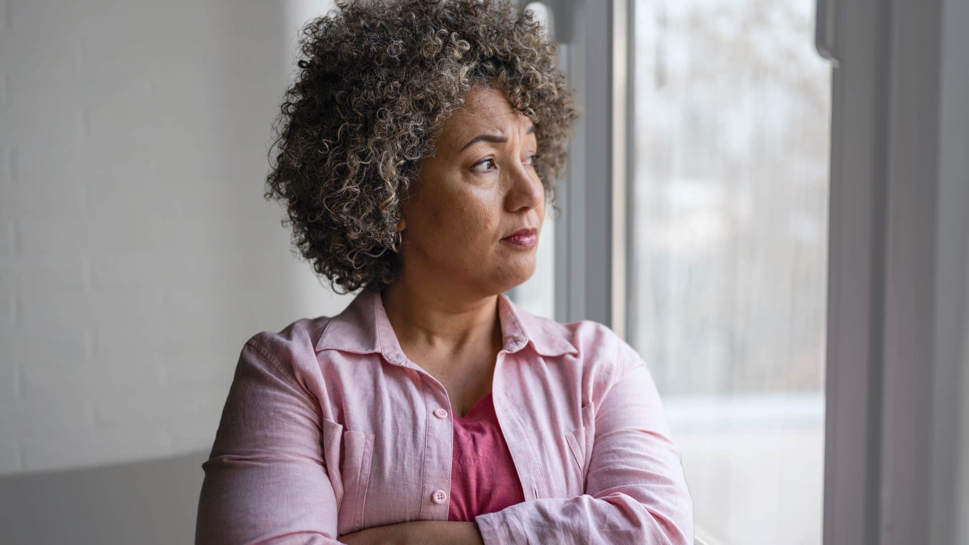 Gen X woman looking serious and staring out a window