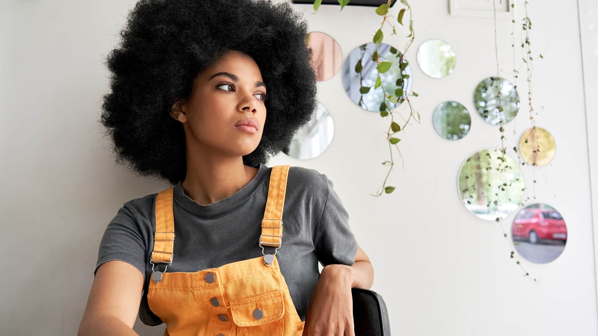 Sad Gen Z woman looking out a window.