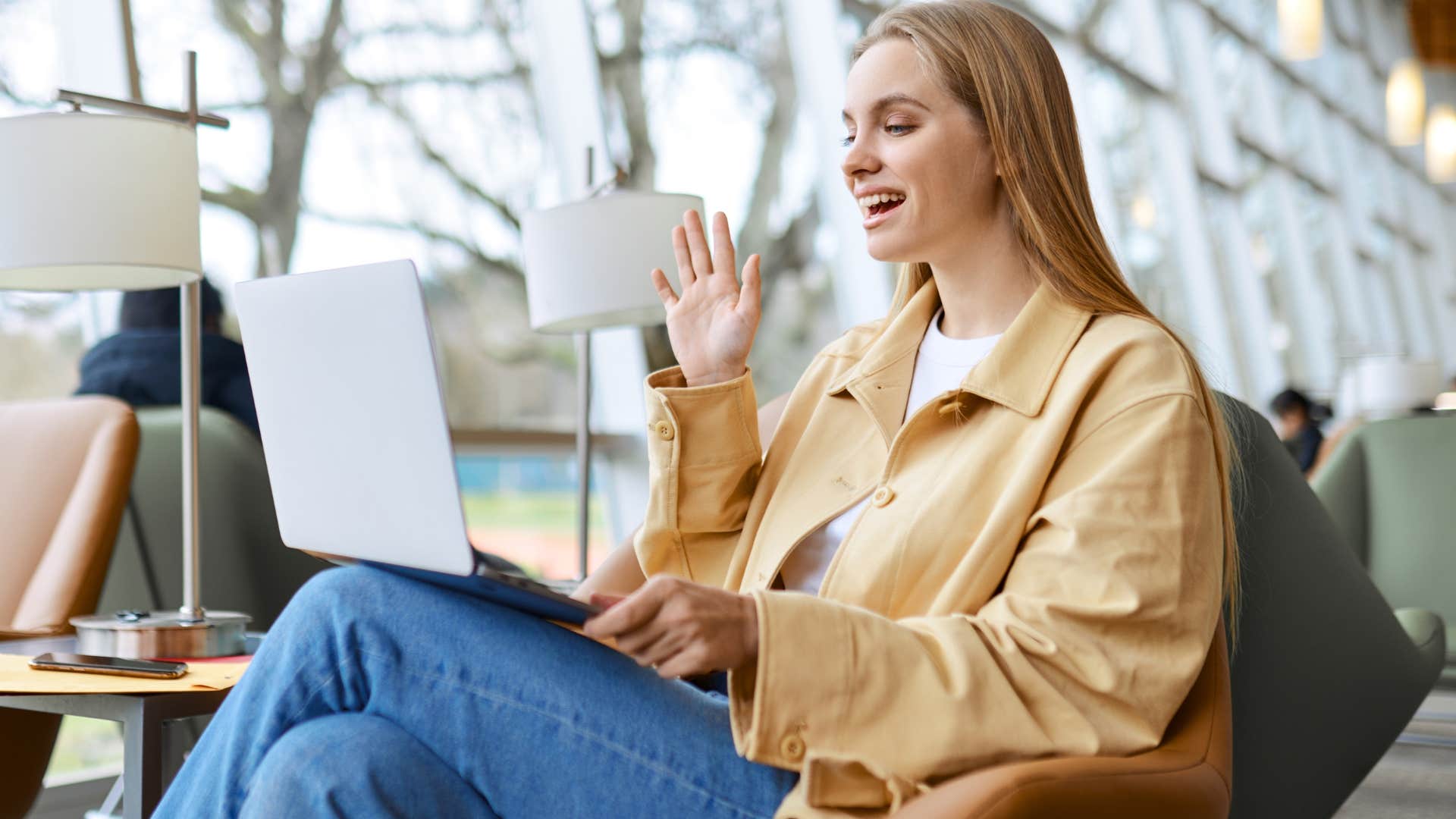 Woman smiling and waving to her laptop.