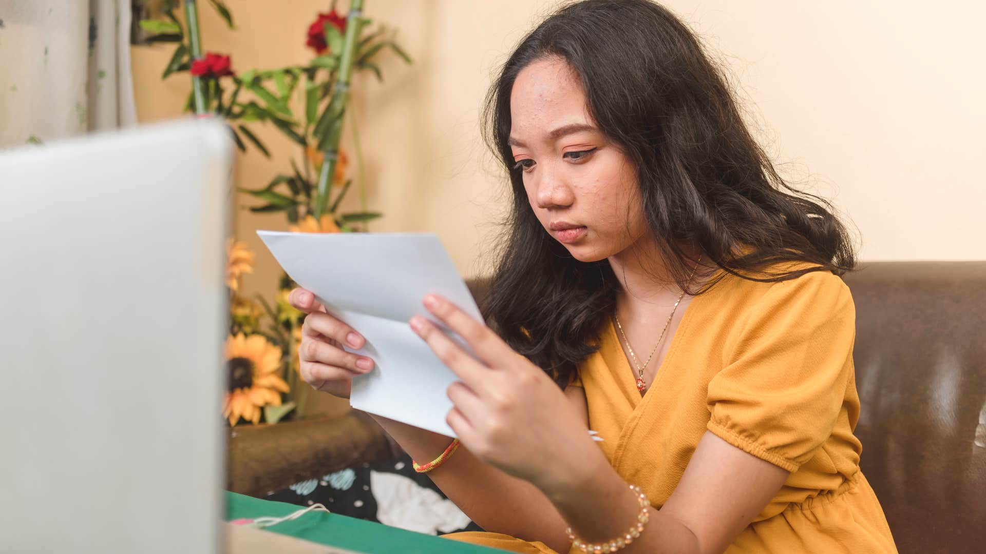 Gen Z woman looking upset staring at a piece of paper.