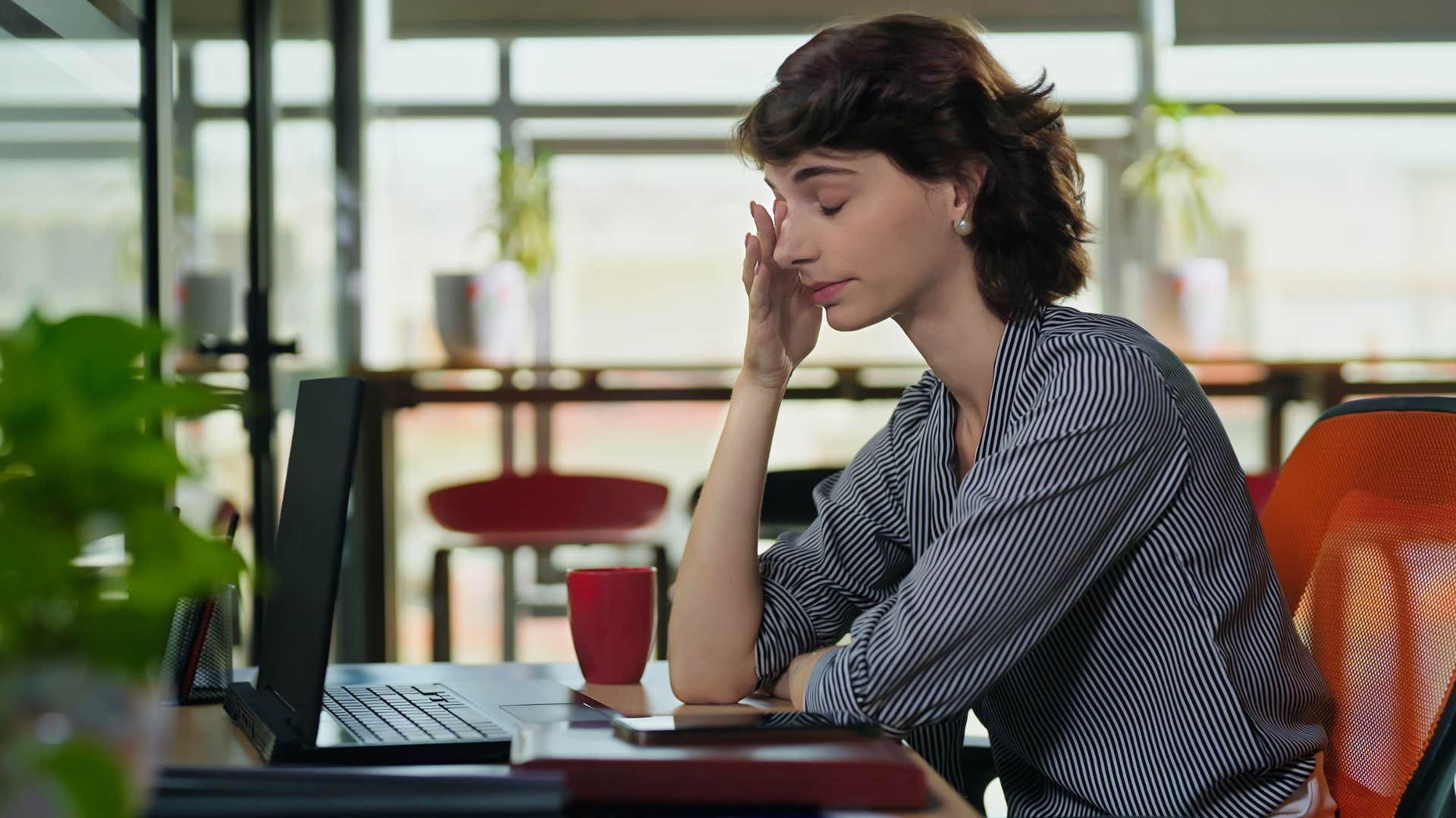 Gen Z woman looking stressed in a coffee shop.