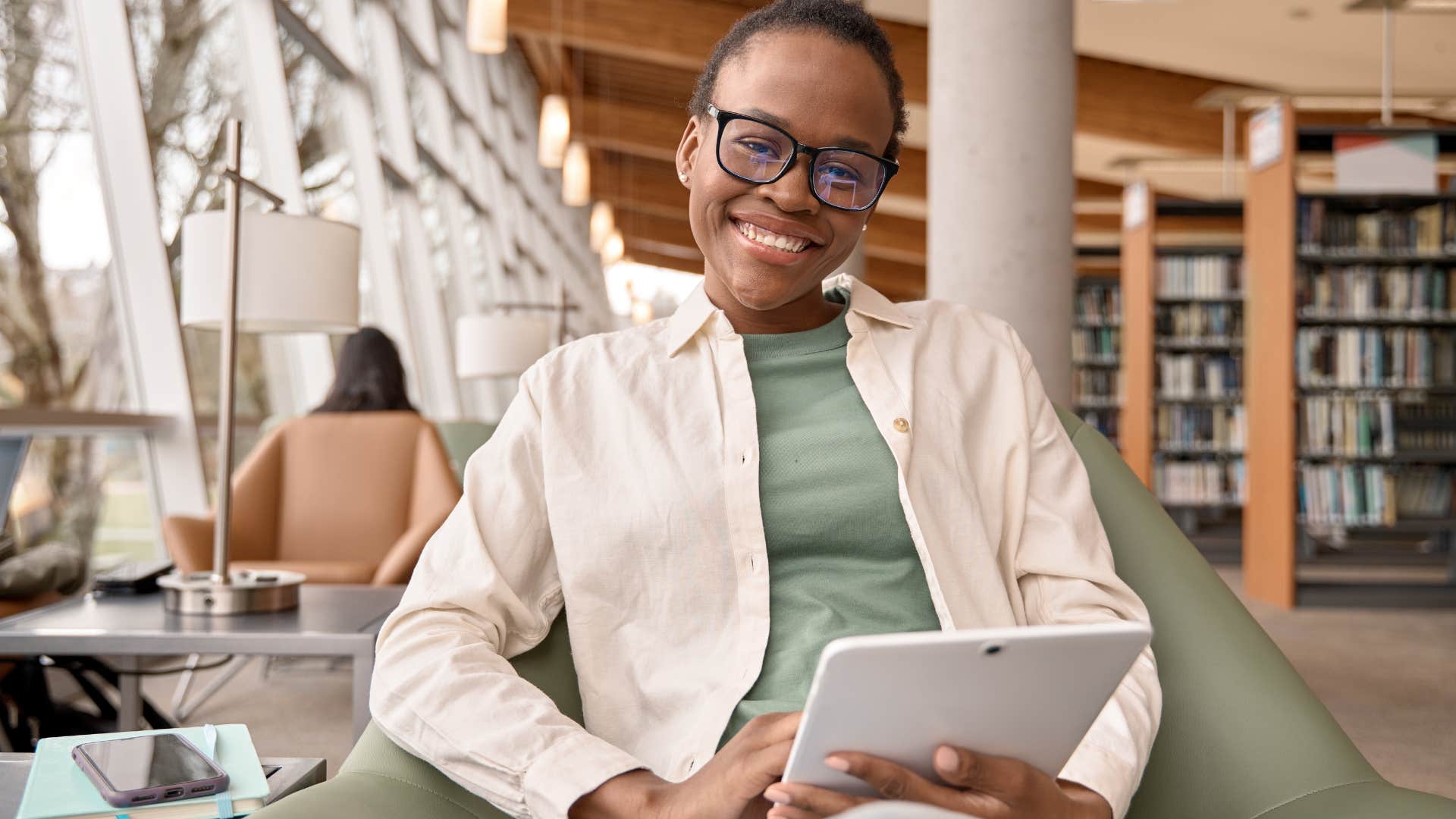 Gen Z woman smiling while holding a tablet.