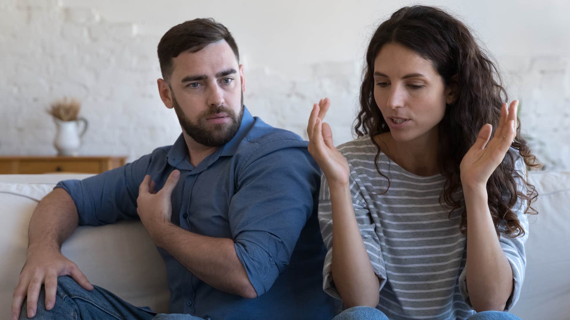 Couple arguing on the couch looking upset.