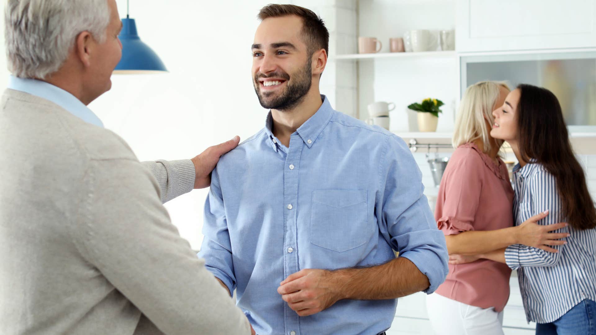 Man shaking his father-in-law's hand in the kitchen.