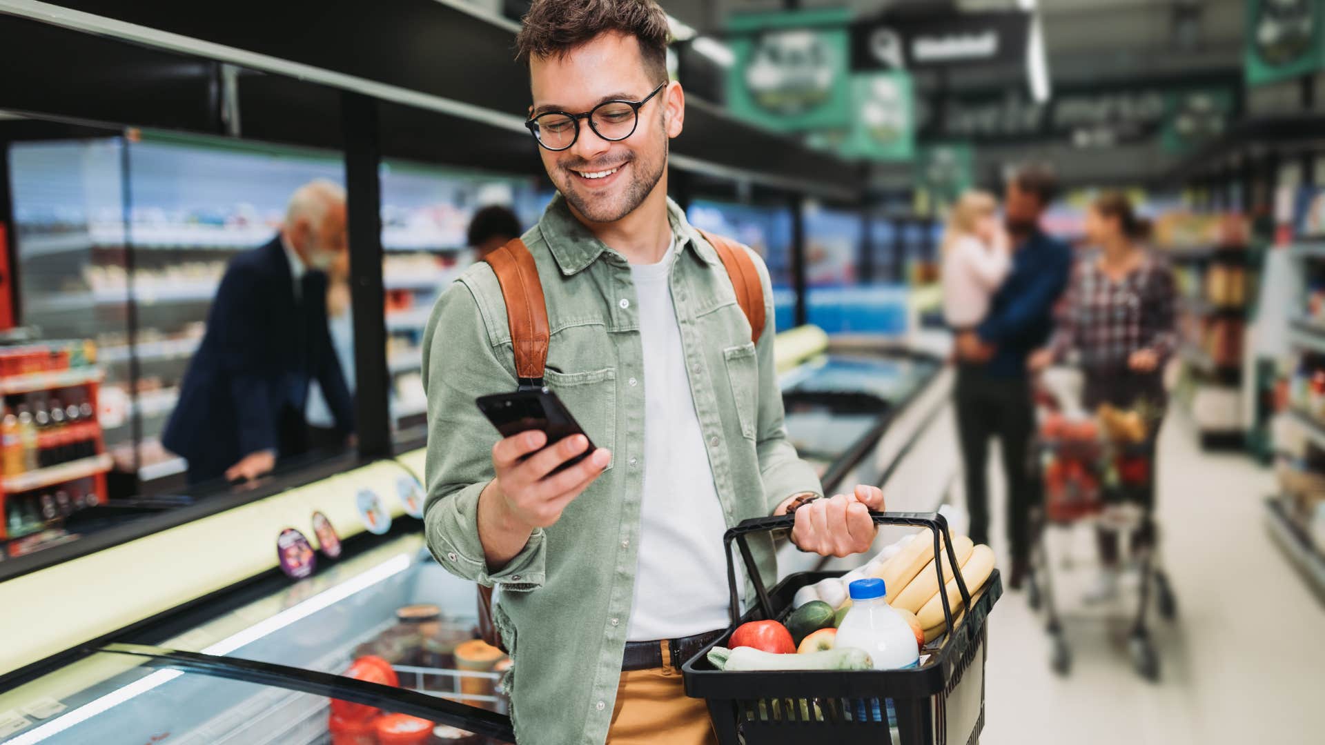 Man texting in a grocery store aisle.