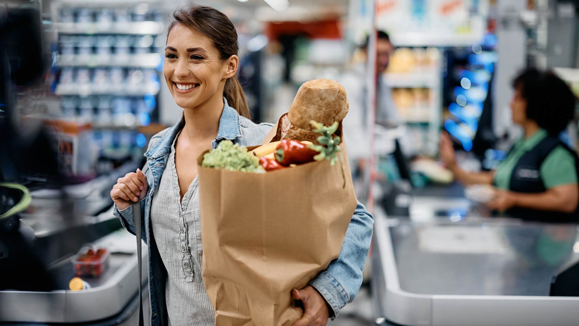 Woman smiling while holding a bag of groceries.