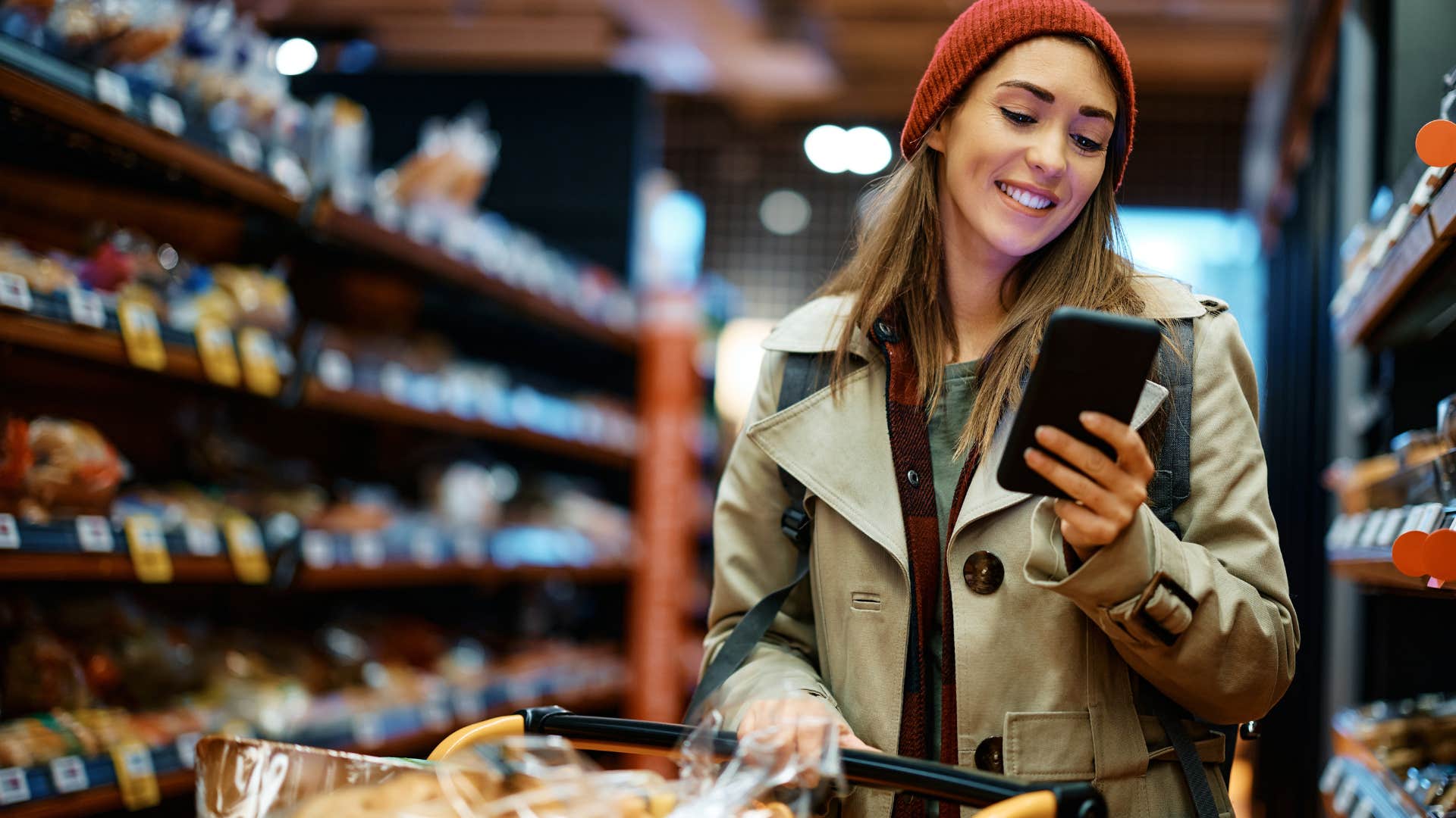 Woman smiling on her phone in a grocery store.