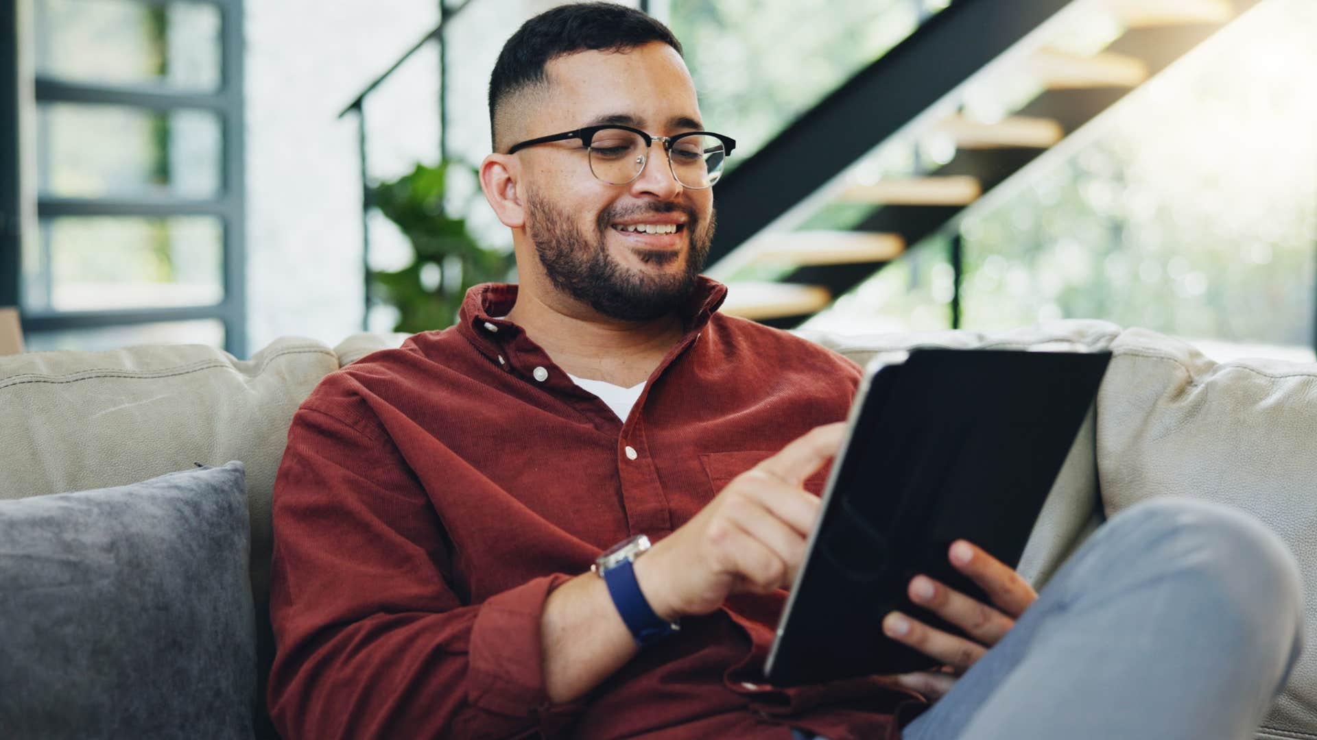 Man smiling while sitting alone on his tablet.