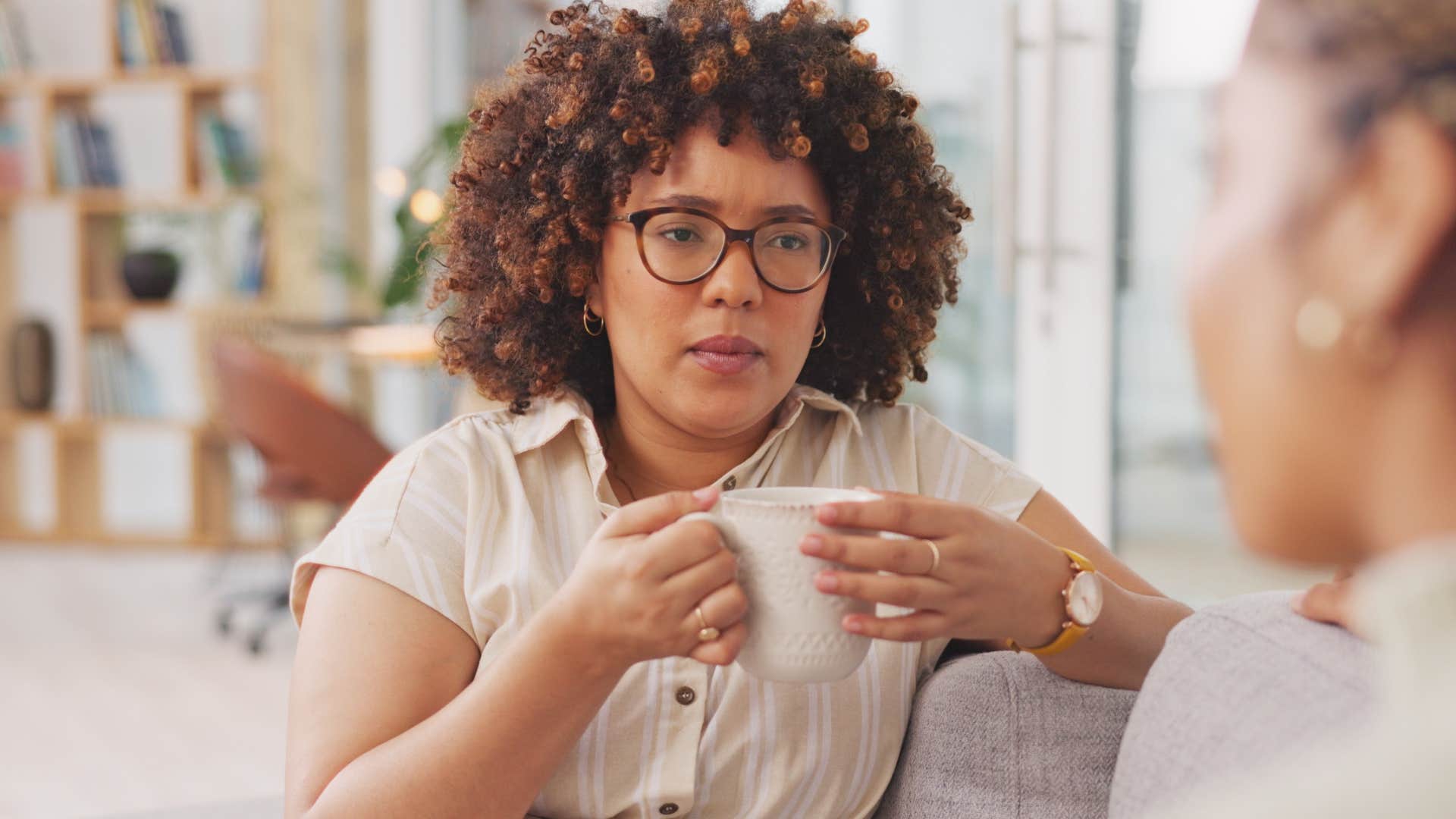 Woman looking serious holding her cup of coffee.