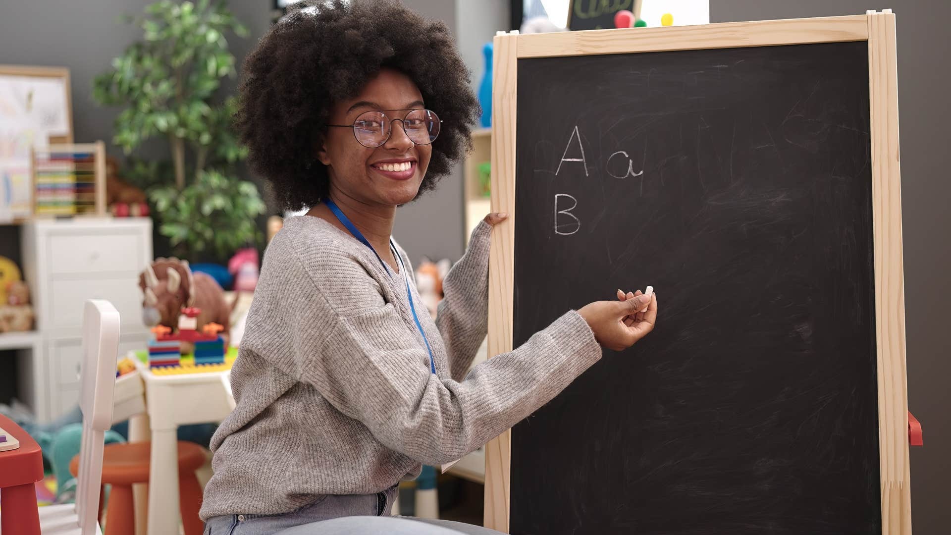 Teacher writing on a small chalkboard and smiling