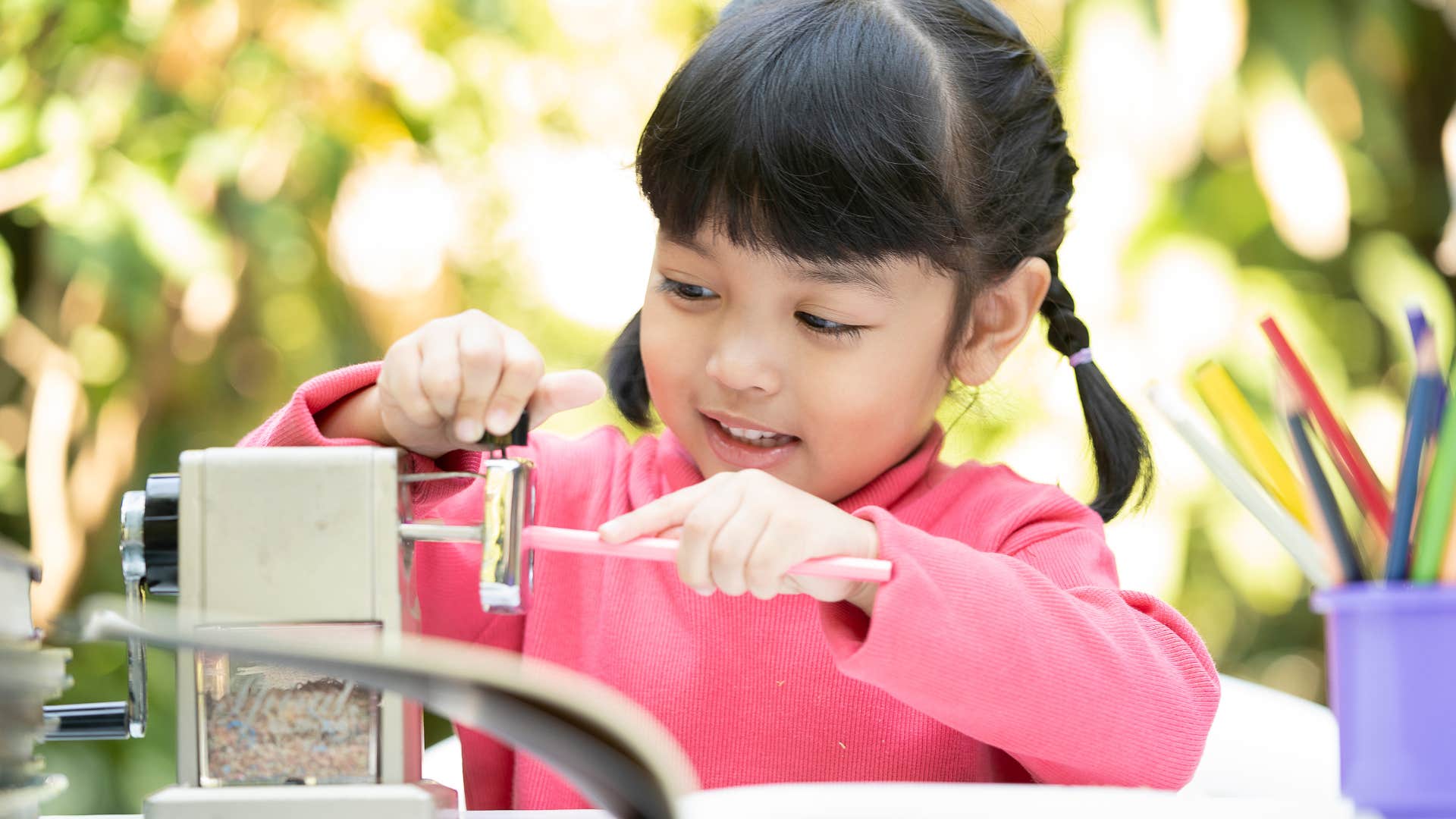 Little girl sharpening her pencil. 