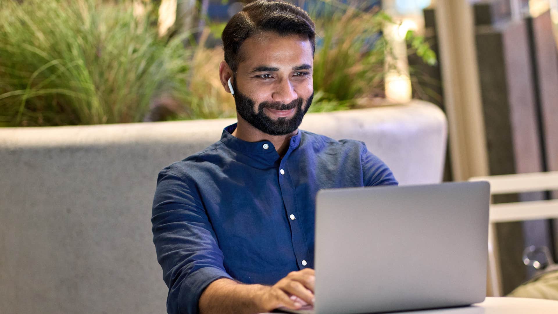 Professional man typing on his laptop and smiling.