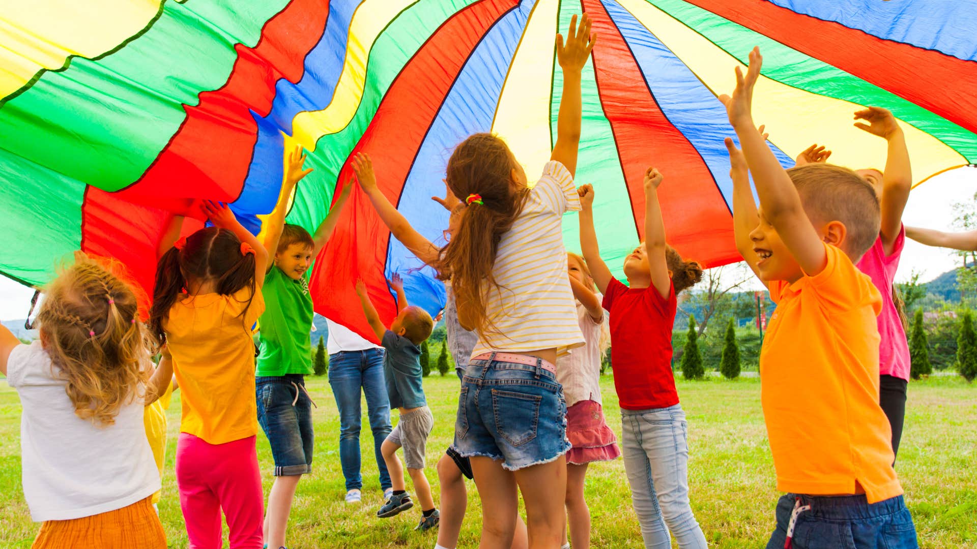 Kids playing under a rainbow parachute