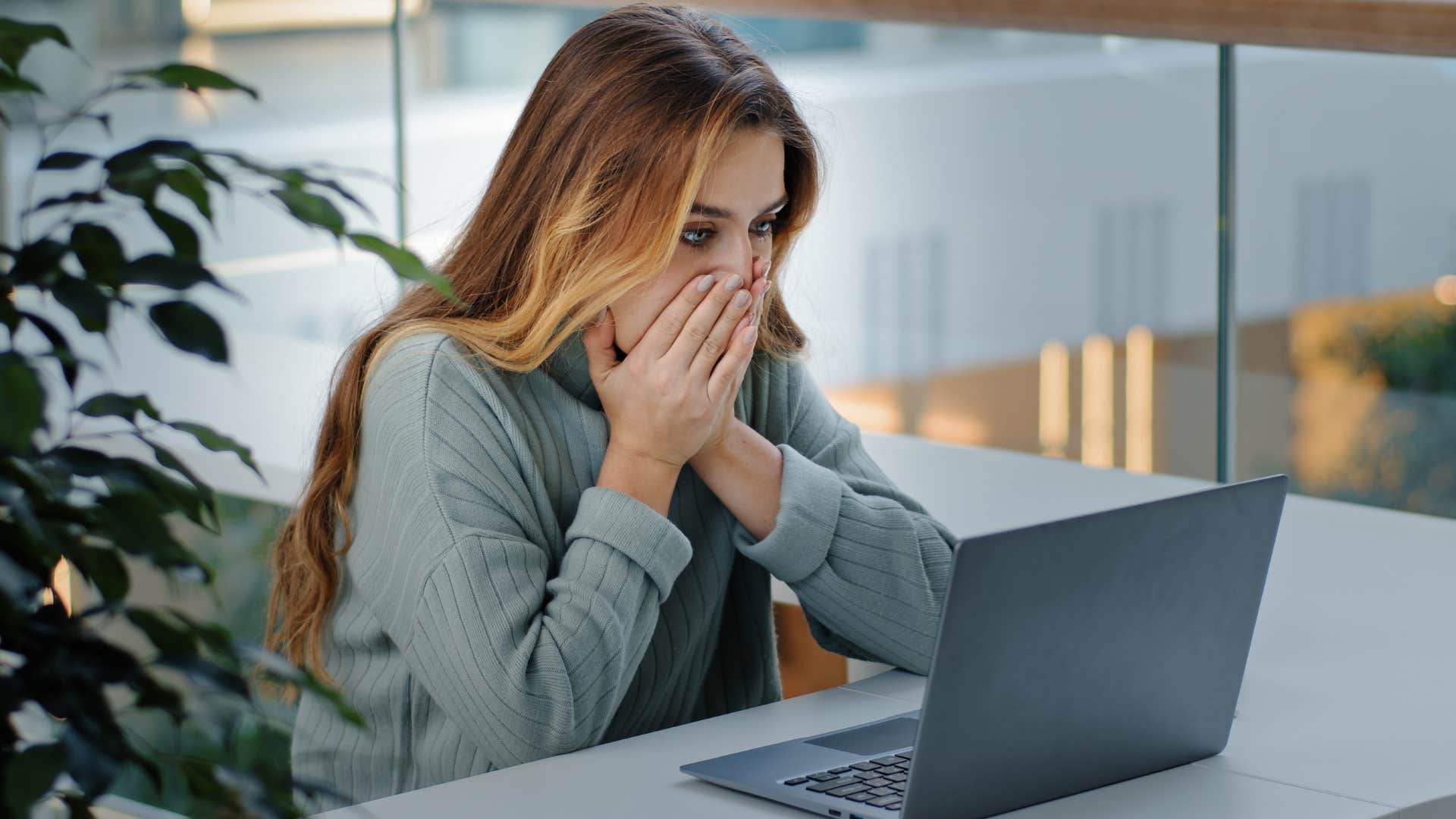 Woman looking shocked staring at her laptop