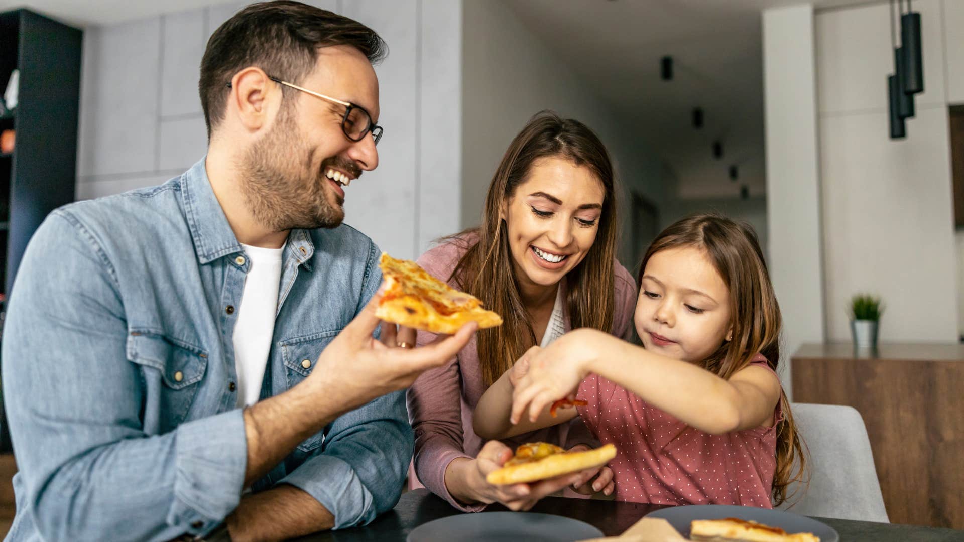 Family smiling and eating fast food at their dining room table