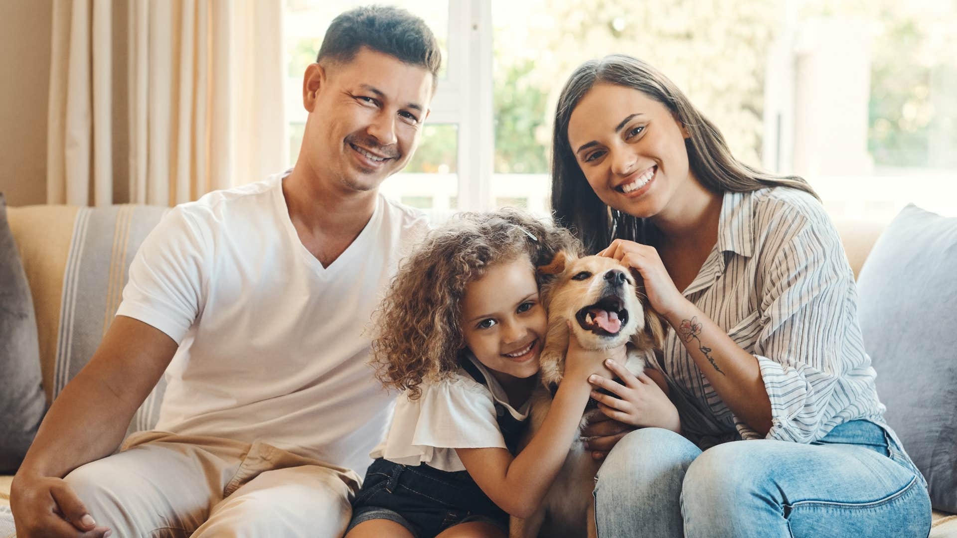 Family smiling on the couch in their home