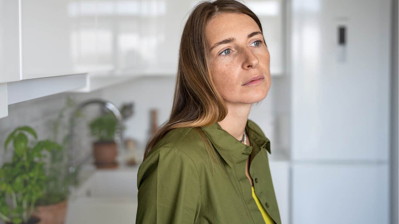 Middle-aged woman looking sad in her kitchen.