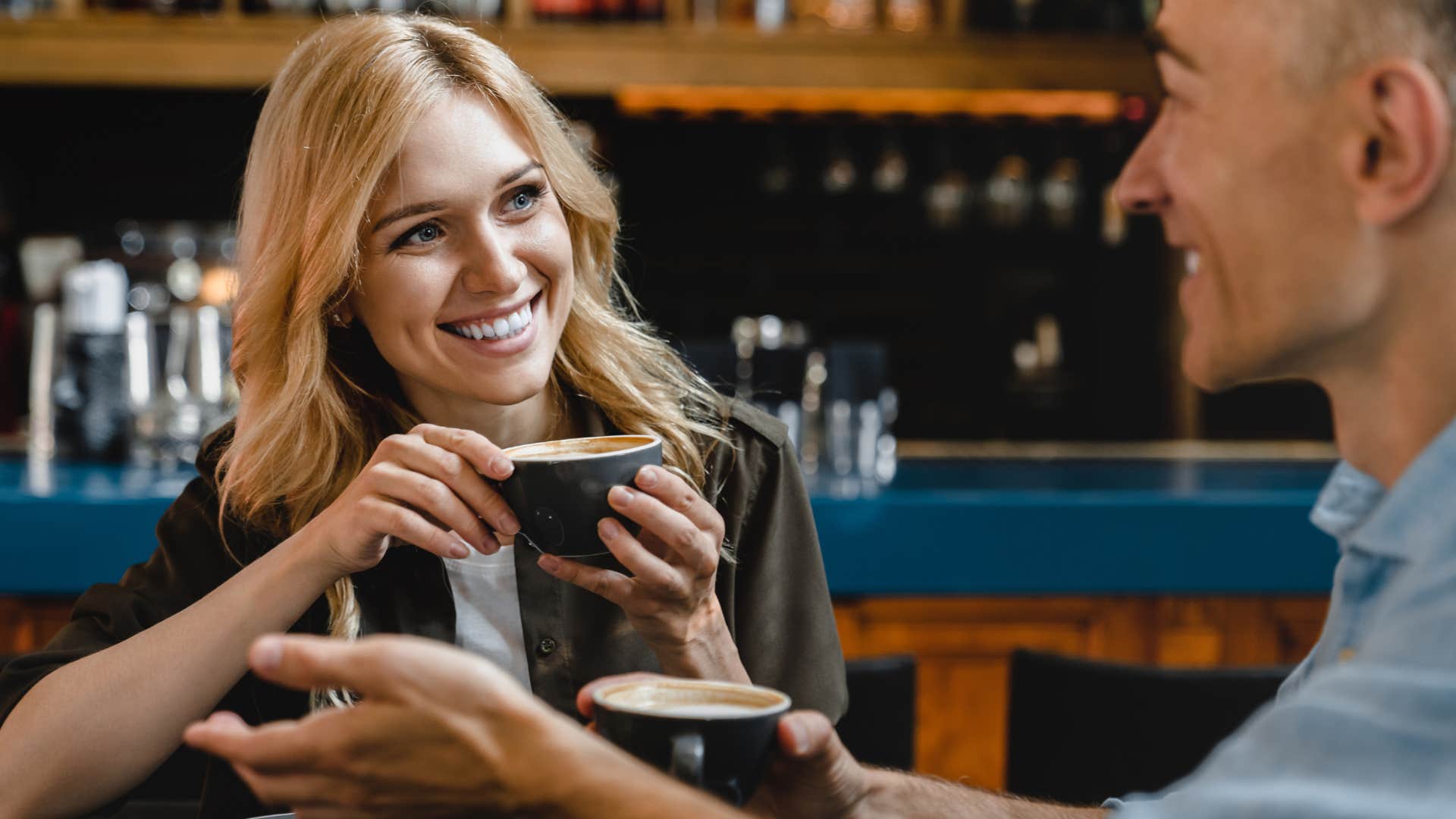 Woman smiling at a man while holding a coffee mug.