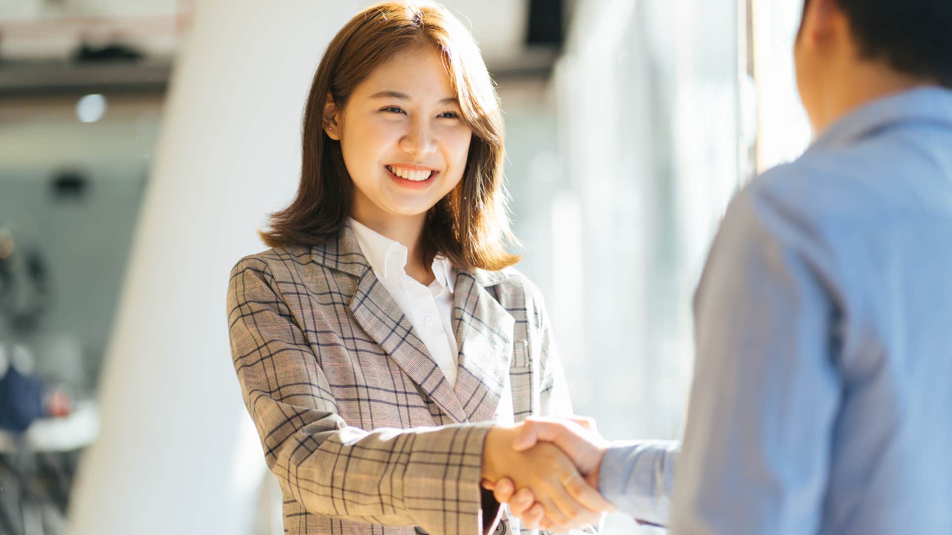 Professional woman smiling and shaking a man's hand. 