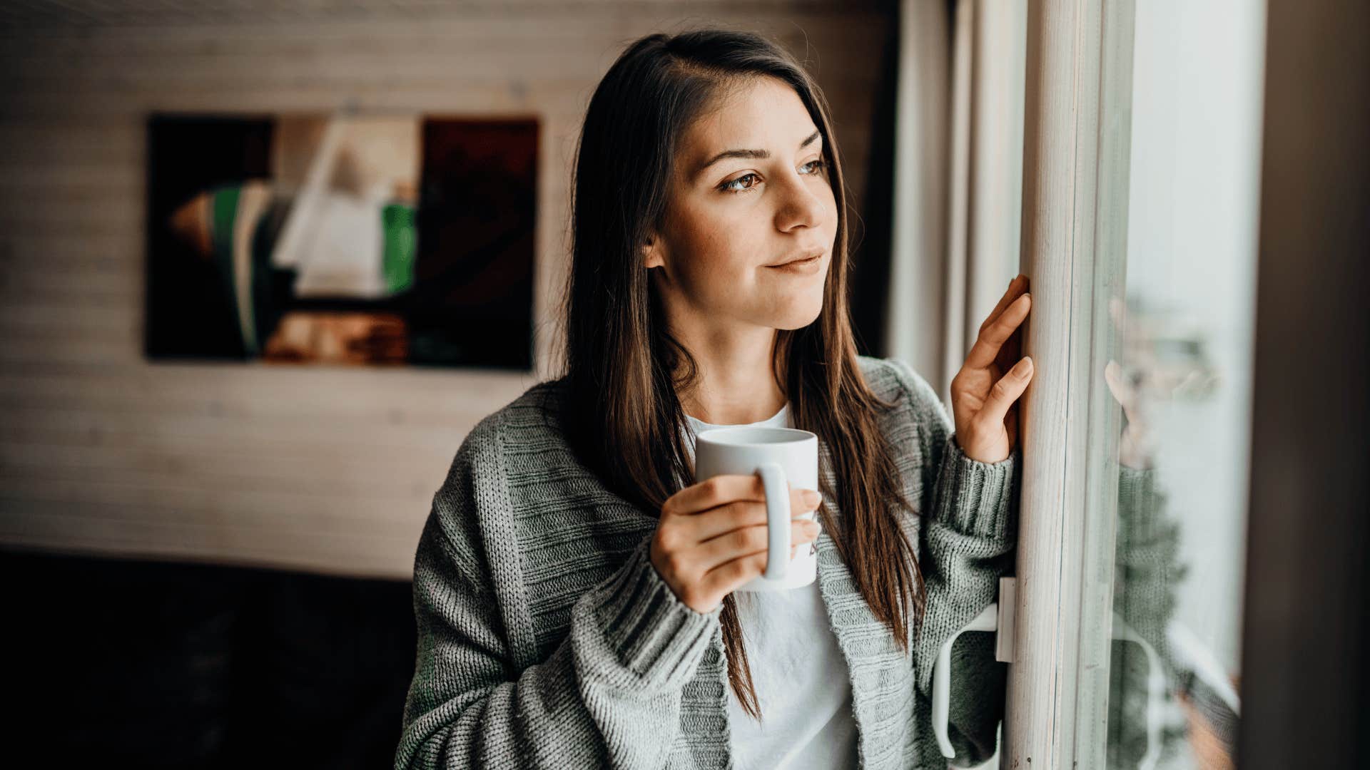 woman drinking coffee and looking out the window