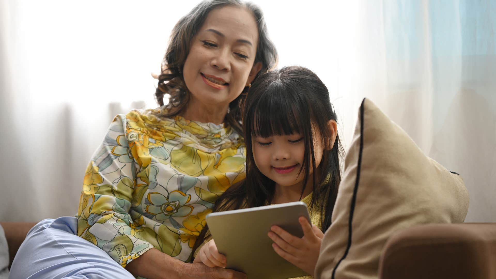 Grandmother smiling and reading with a young girl. 