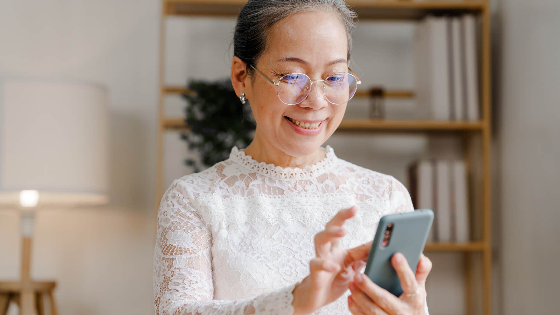 Older woman smiling and typing on her phone. 