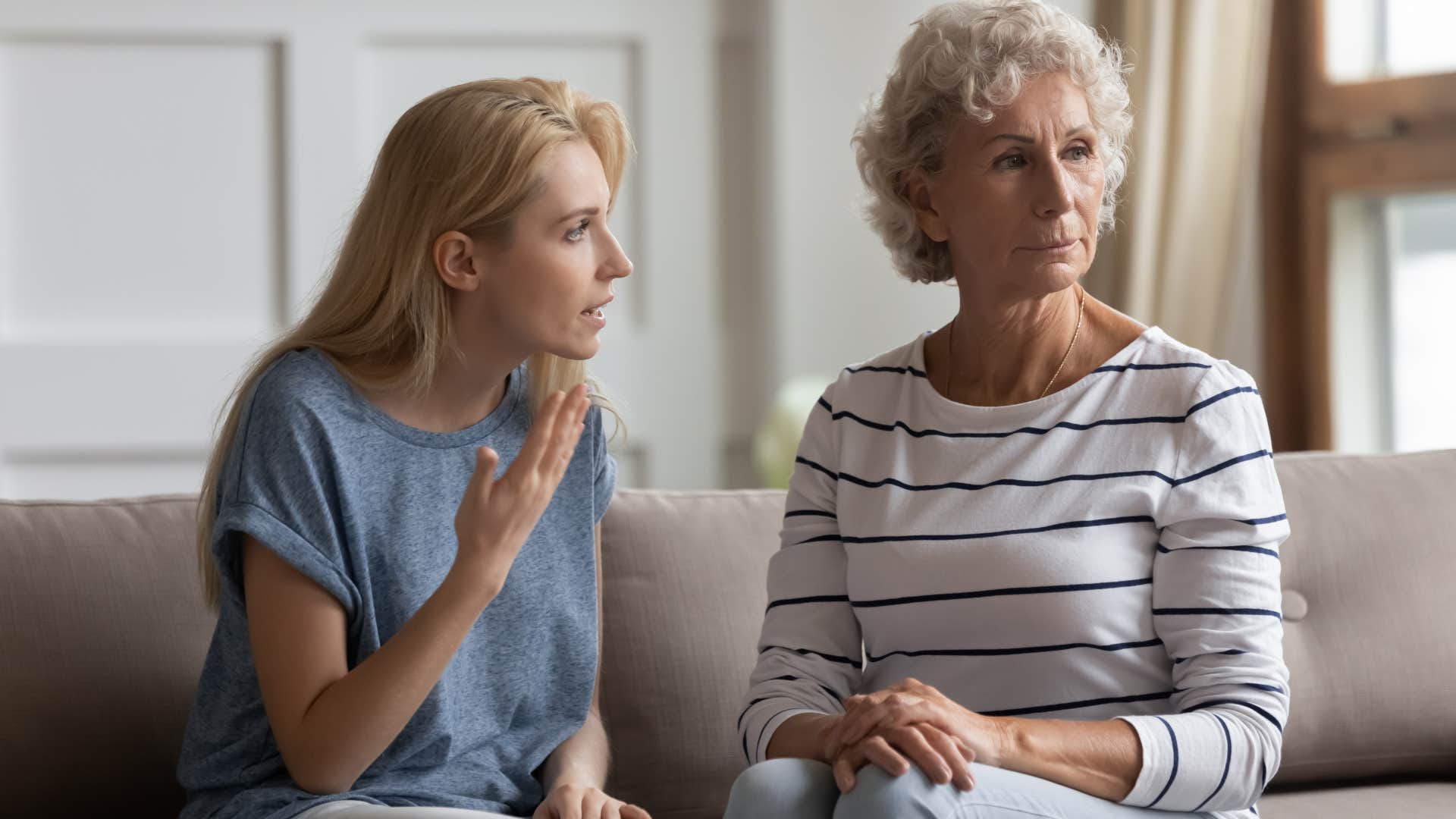 Upset adult daughter talking to her mom on the couch.