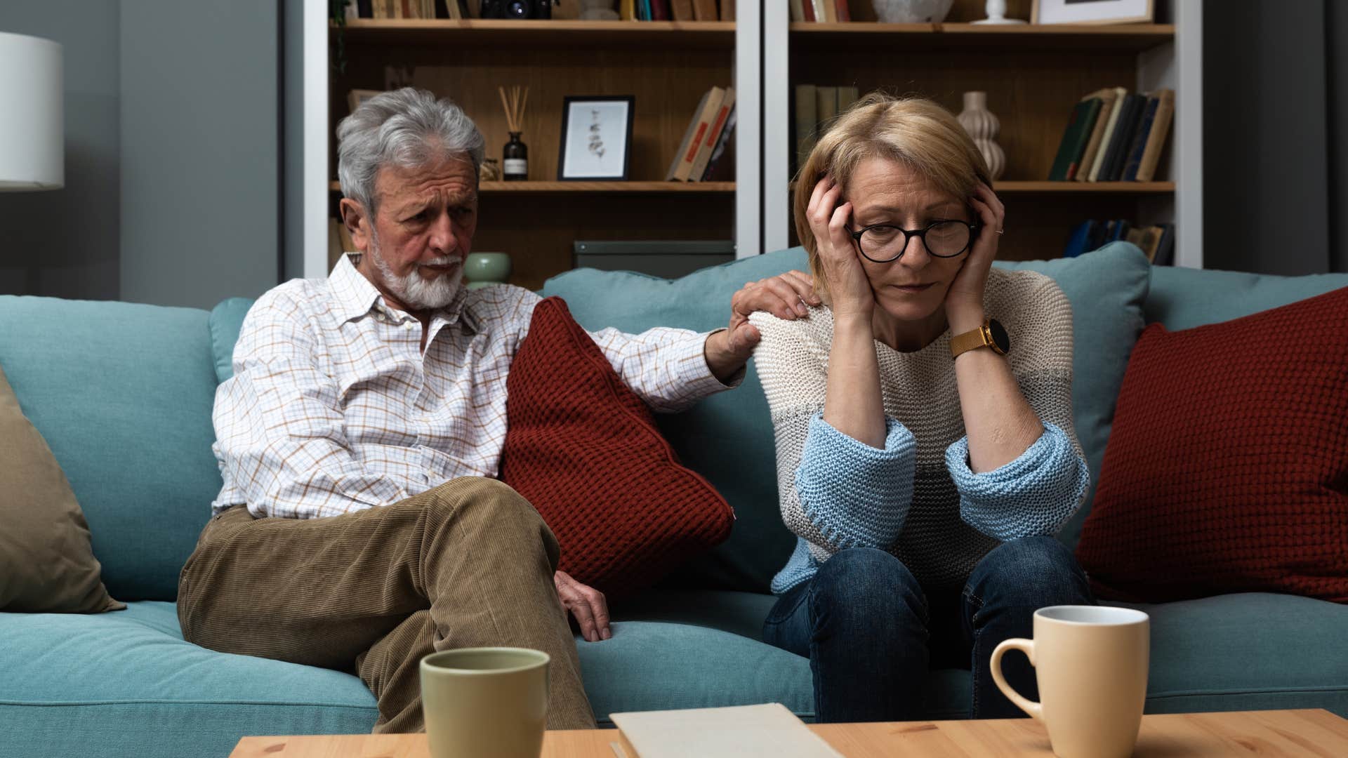 Older couple looking upset sitting together on the couch.