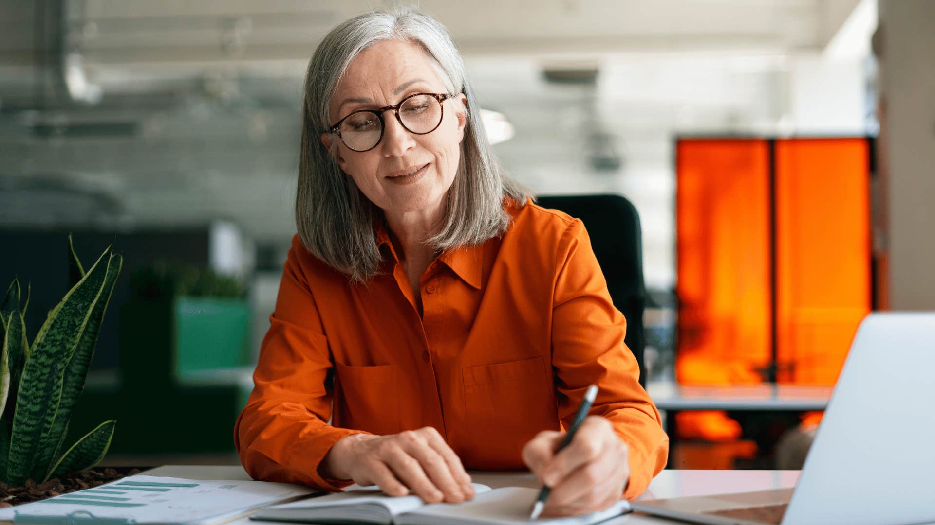 woman writing in notebook at work 