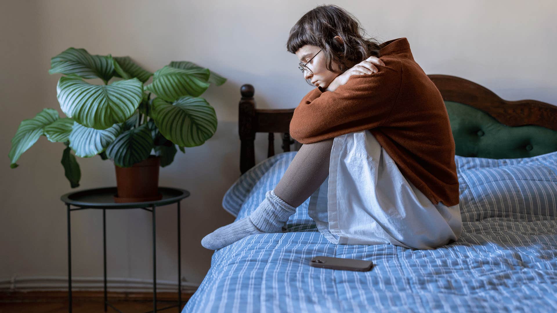 woman contemplating while sitting down on bed