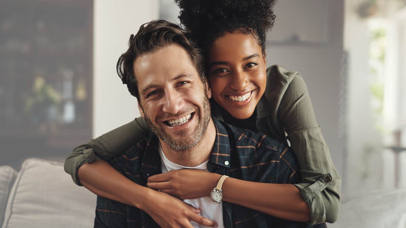 Smiling woman hugging her partner on the couch.