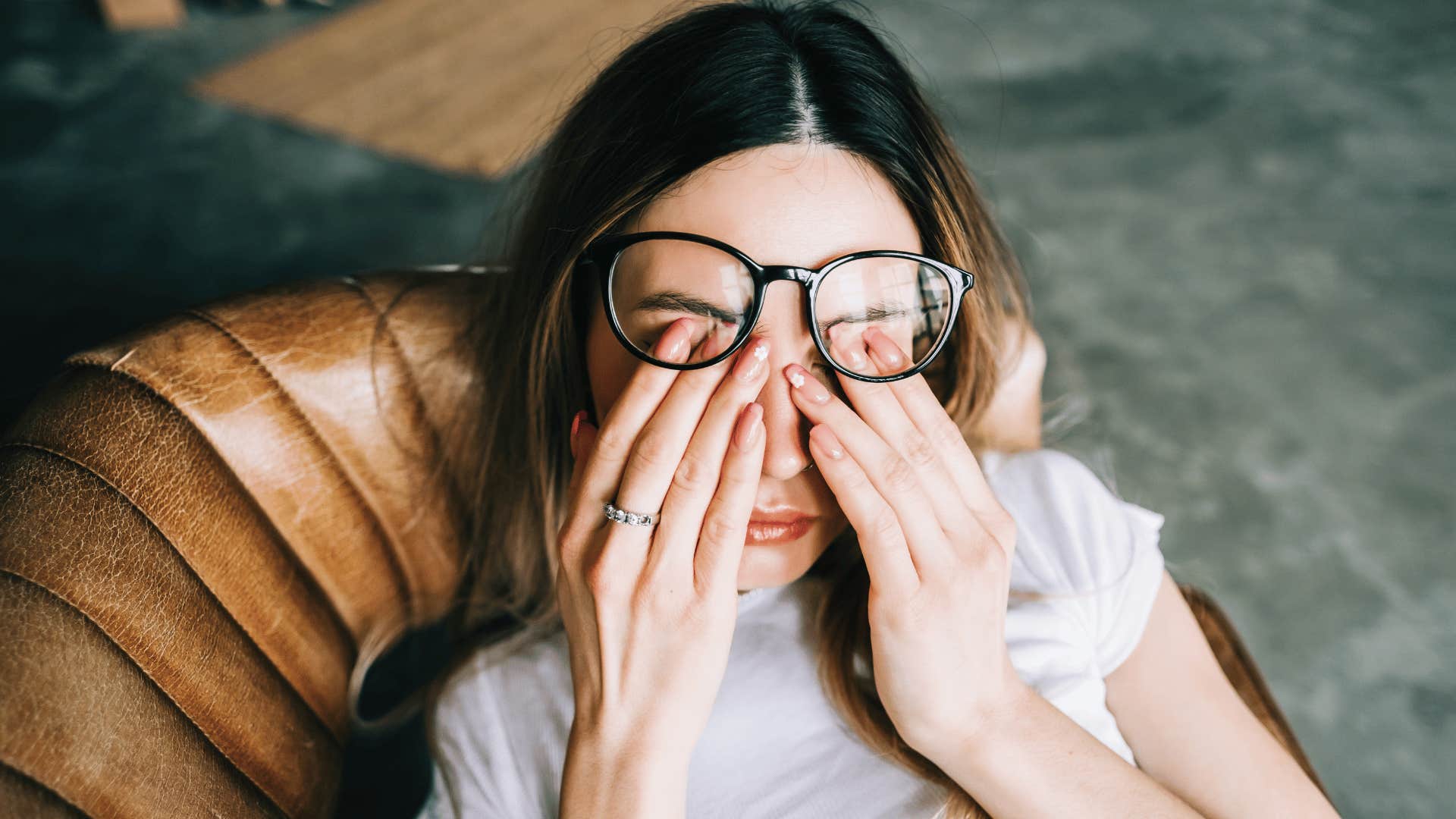 stressed woman rubbing her eyes under glasses