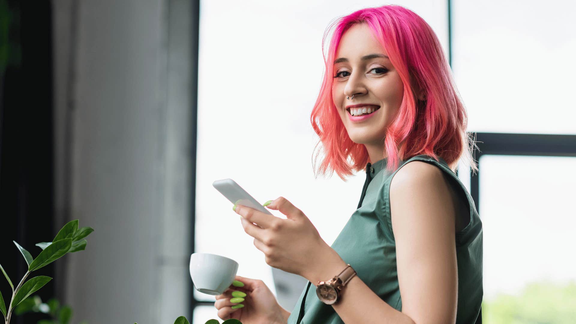 woman with pink hair on phone smiling at camera 