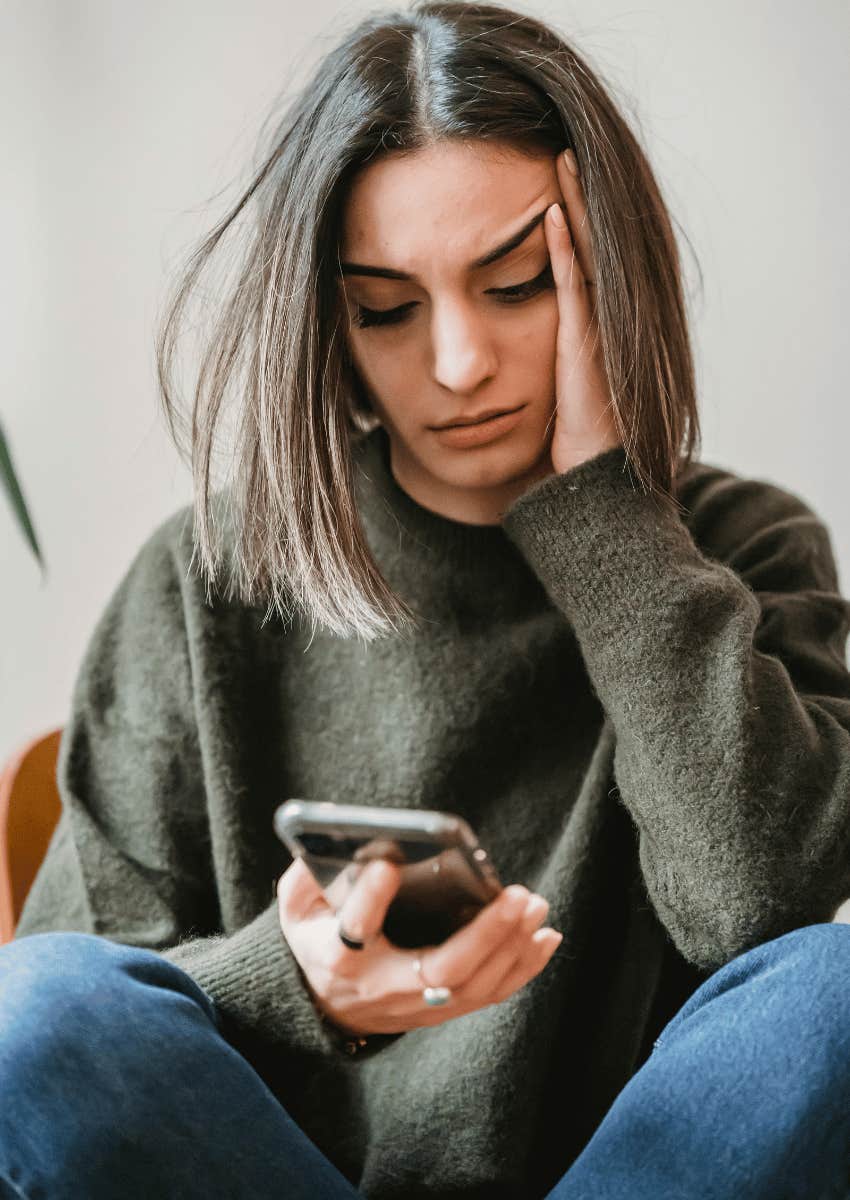 upset woman staring down at her phone