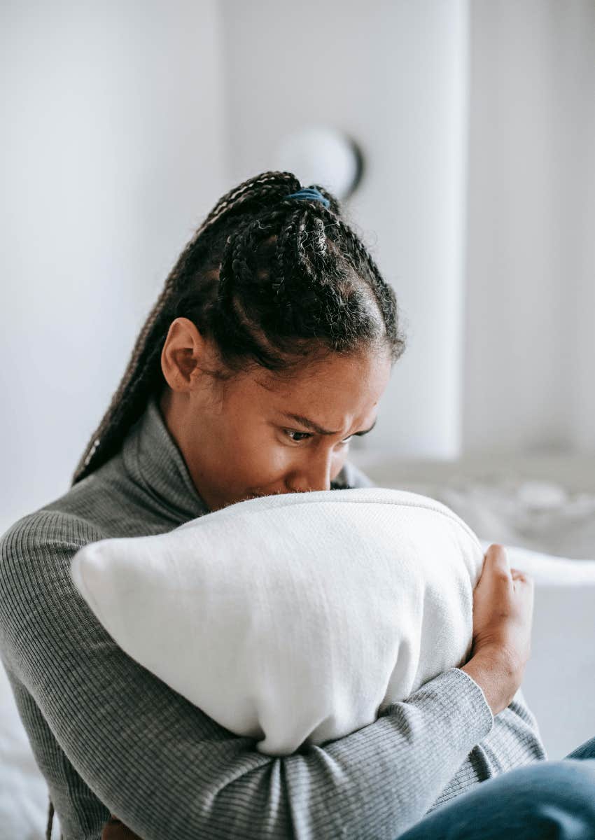 upset young woman hugging a pillow to her chest