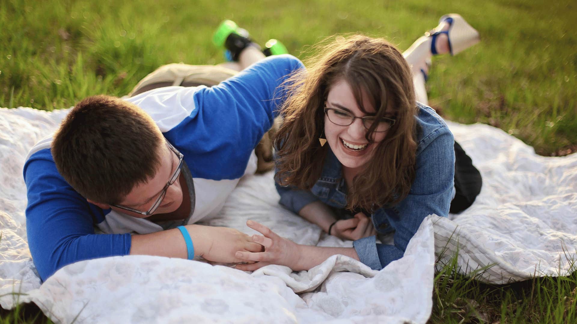 couple laughing together on a blanket outside