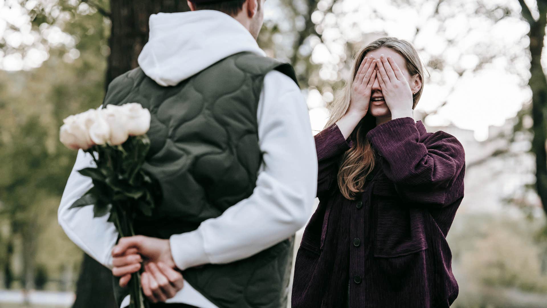 man surprising woman with flowers