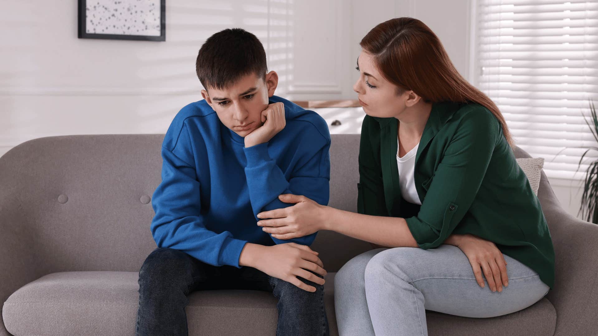 mother and son talking on couch while mother comforts him 