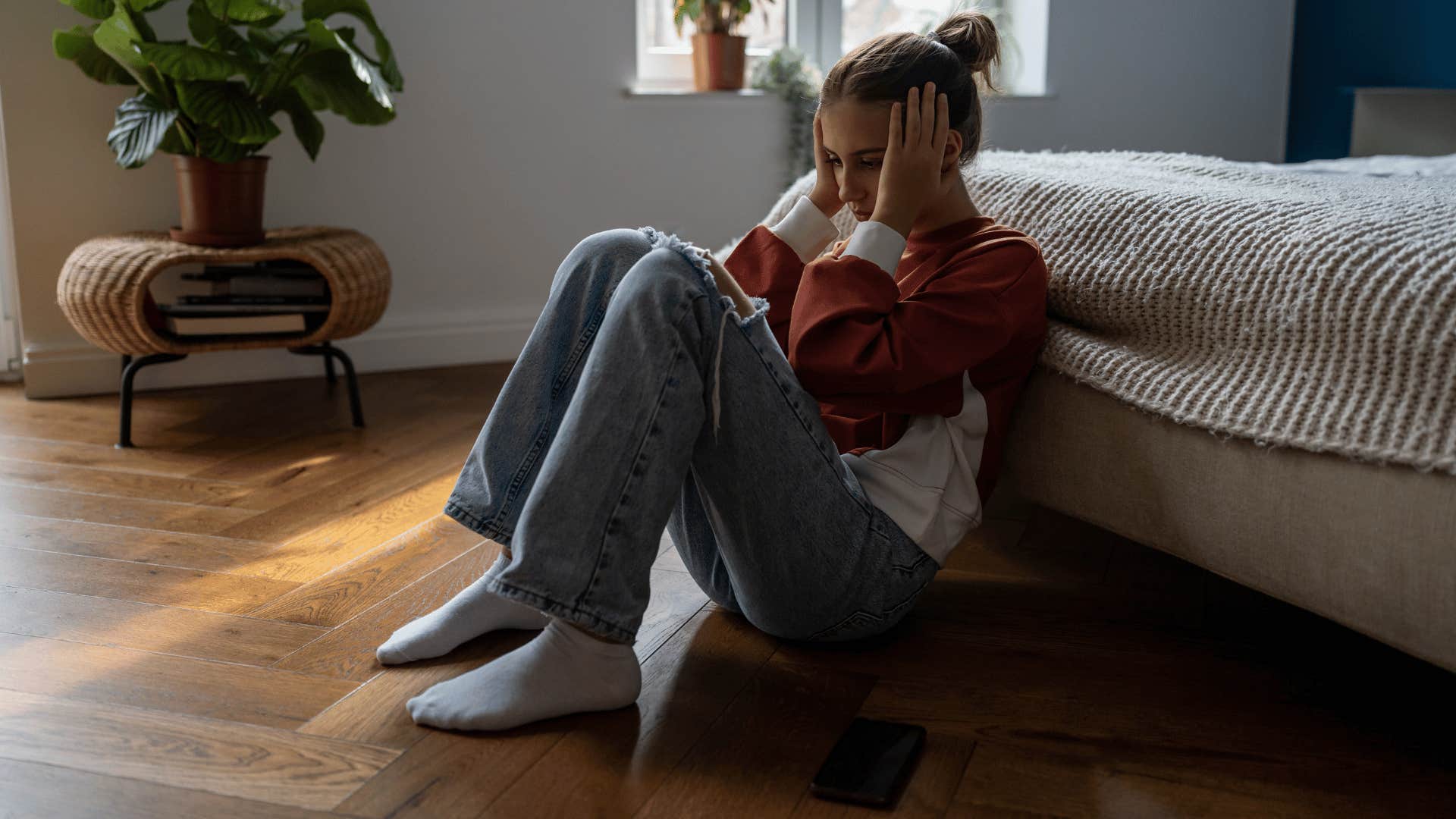 young woman sitting on floor upset 