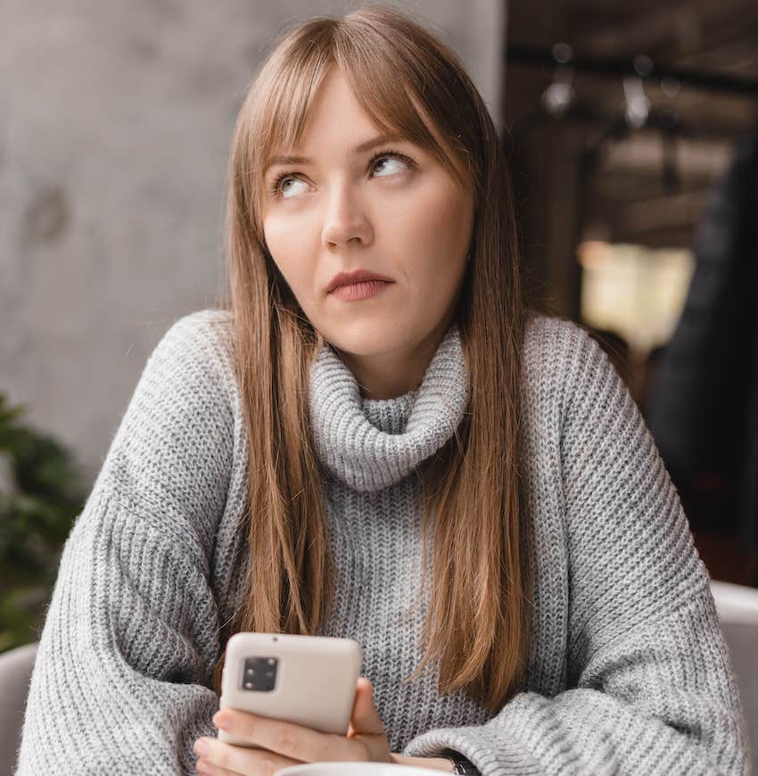 Woman holds her phone and rolls her eyes