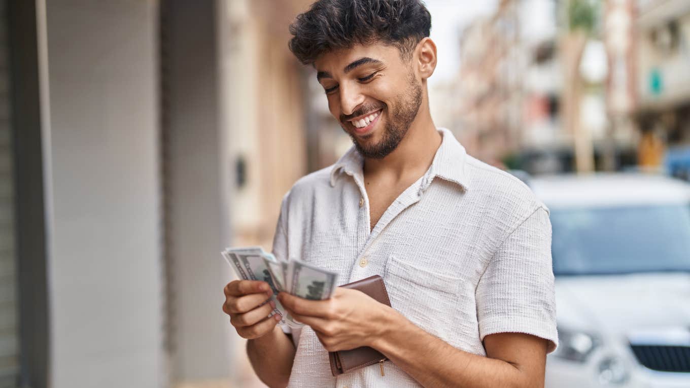 man standing in street counting money