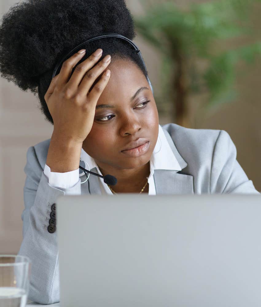 woman at work holding her head looking off into the distance