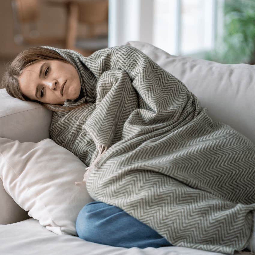 woman laying on a couch wrapped in a blanket